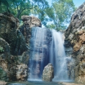 This 12-foot waterfall and surrounding rock formations were constructed to appear as if the waterfall had eroded the limestone formation over eons of time. The air bubbles in the falling waterfall are illuminated by the sunshine, and the reflecting sky causes the water to appear an even deeper blue.