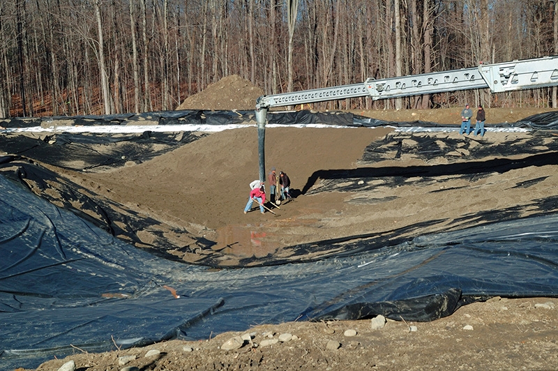 The “bank run” gets installed on top of the pond liner. This material will ultimately be compacted, providing a solid base to walk on and appear as the bottom of a clean streambed.